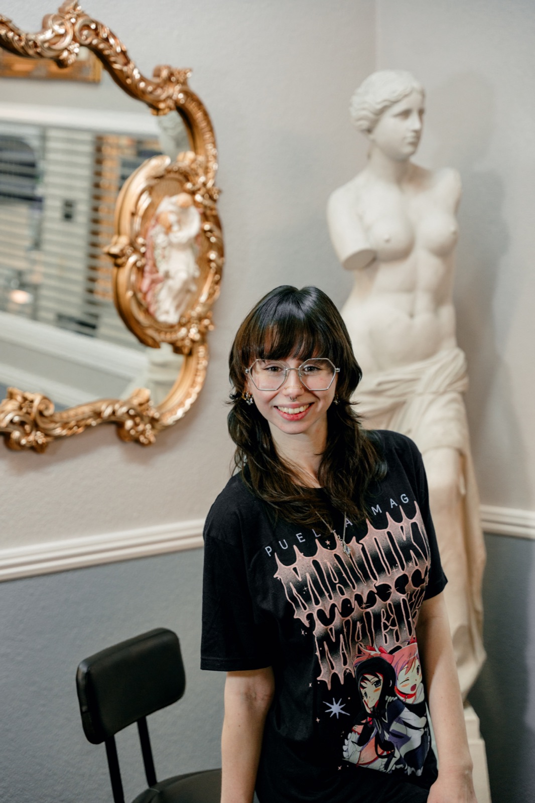 Juniper smiling beside an ornate gold mirror in the studio